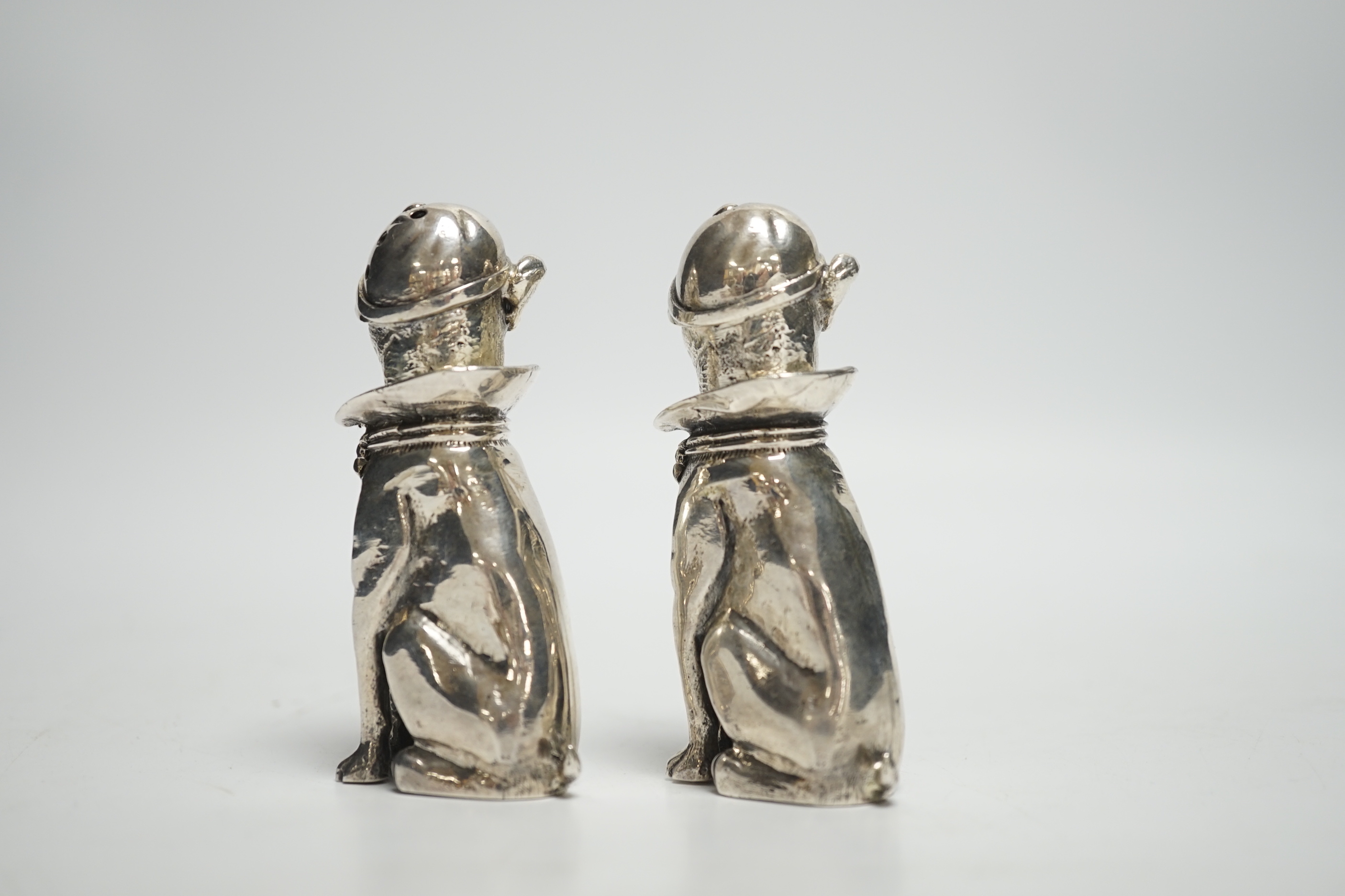 A novelty pair of 925 pepperettes, modelled as seated dogs, wearing caps, 76mm, 6.3oz.